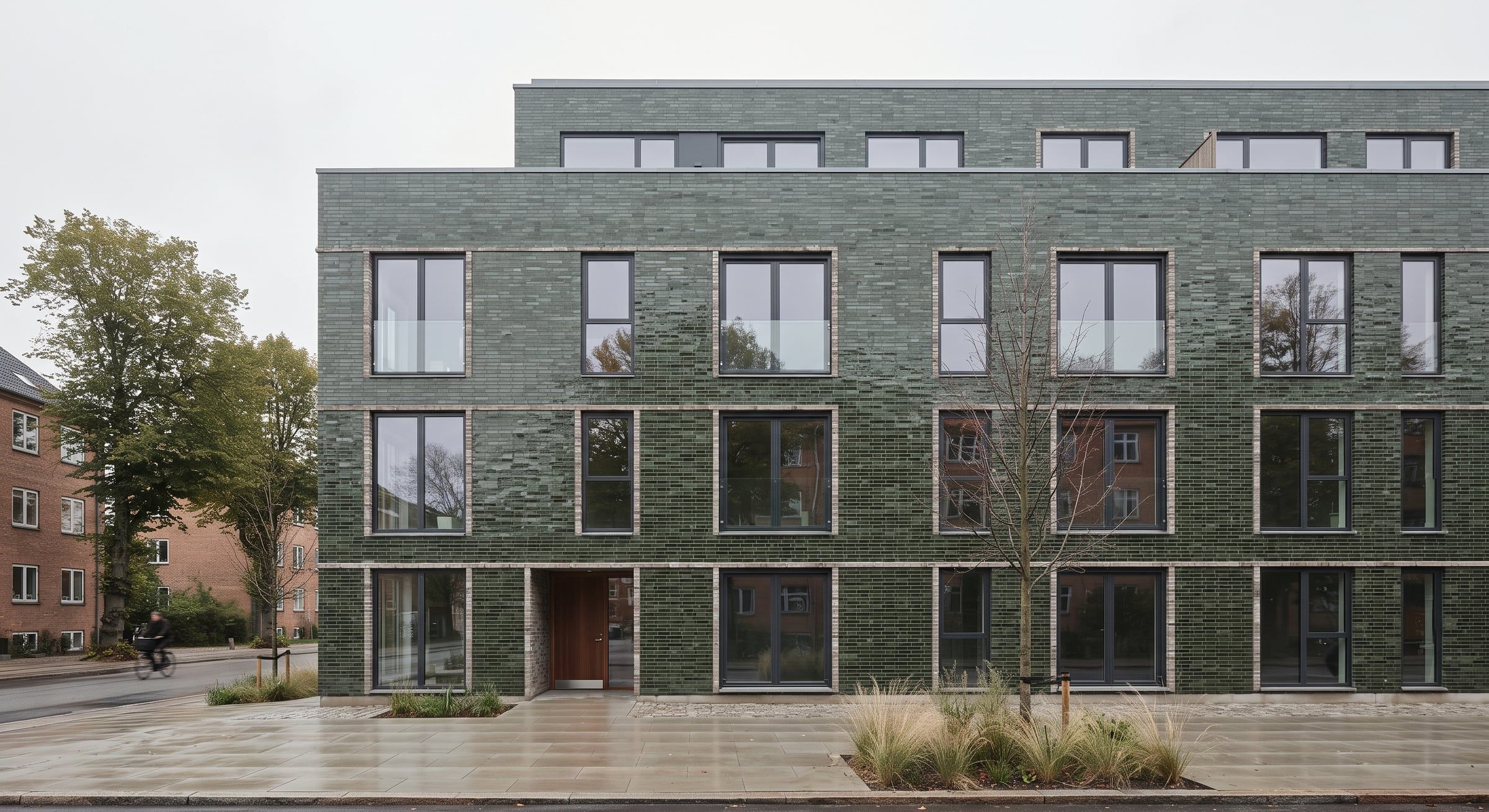 Etagebyggeri i fire etager med facade af grønglaserede sten.