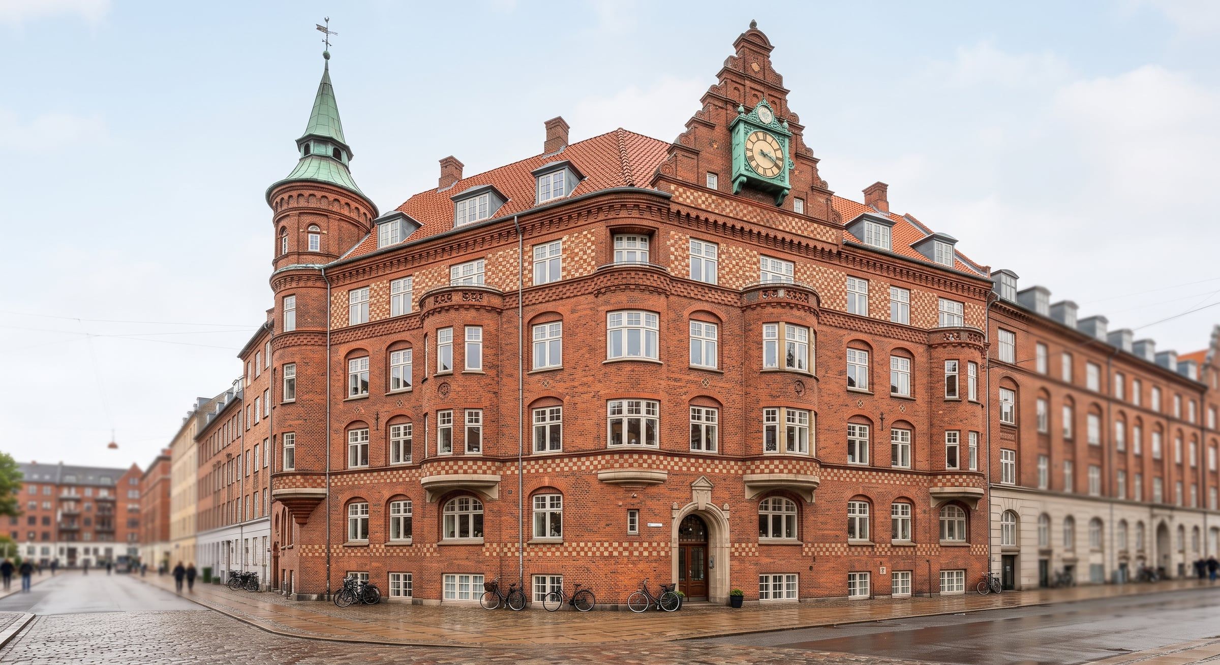 Stor nationalromantisk hjørneejendom i røde sten med tårn, gavle og mange sprossede vinduer.