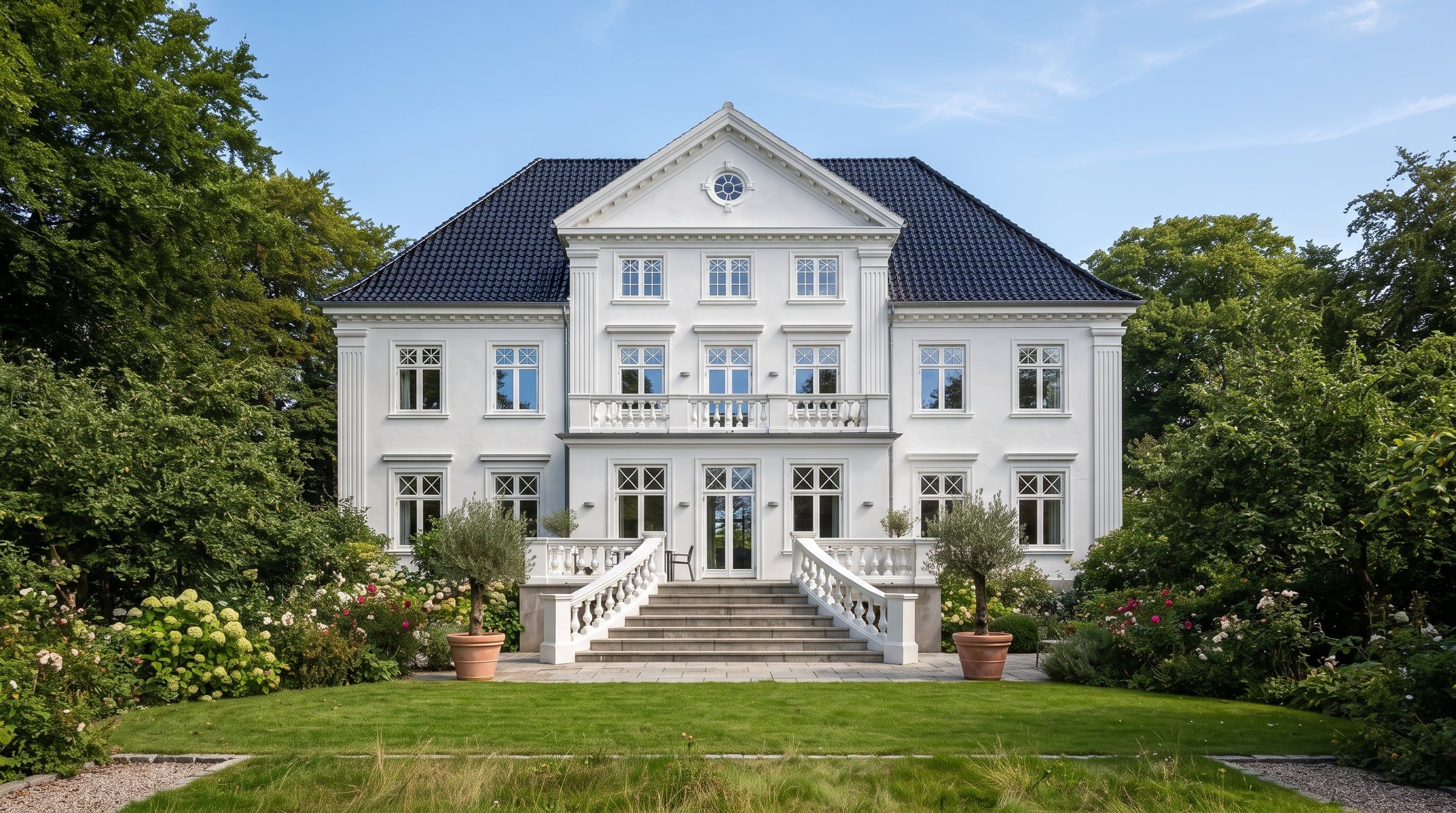 Hvid patriciervilla med sort tag, bred trappe og have.