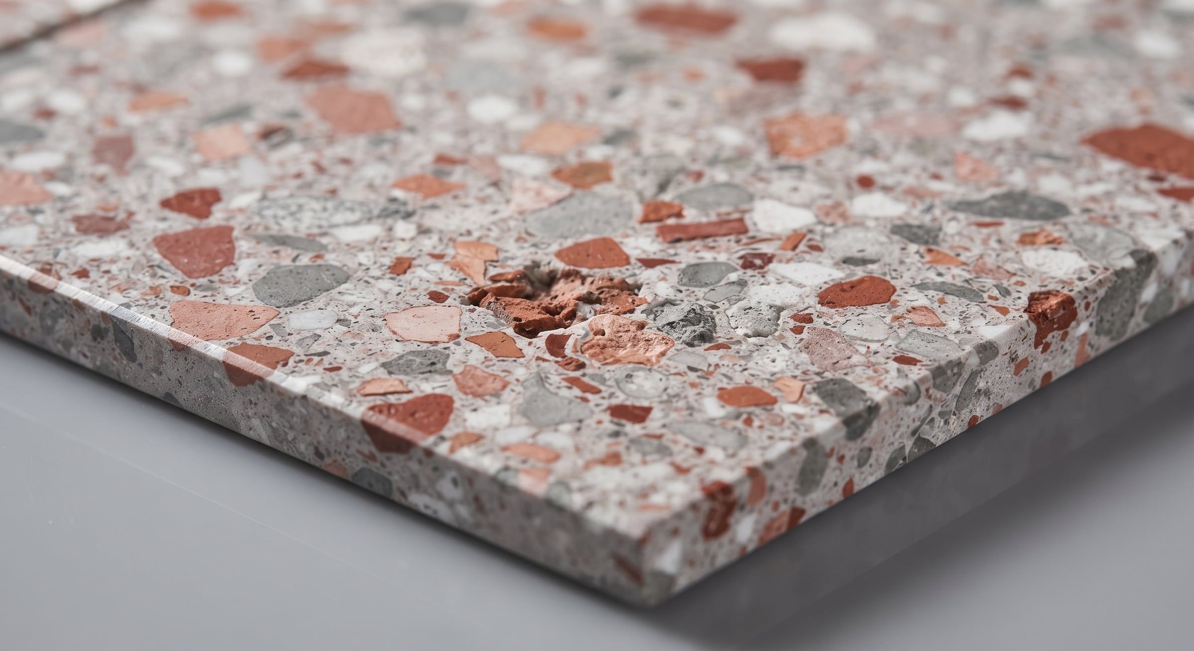 Slebet plade med terrazzo-mønster af røde, grå og hvide korn.